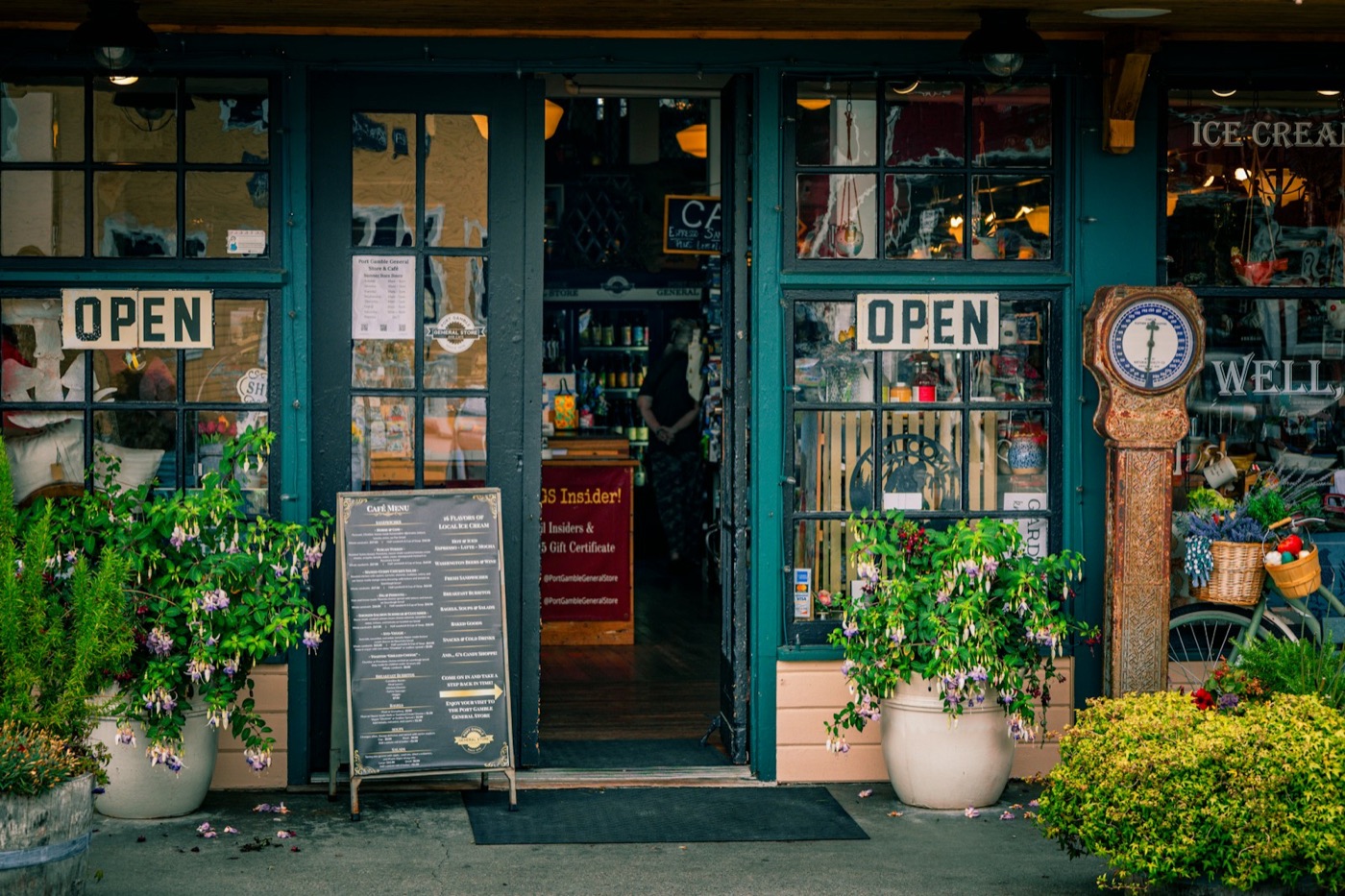 Restaurant shopfront with open signs, a chalkboard menu and flower pots by the door