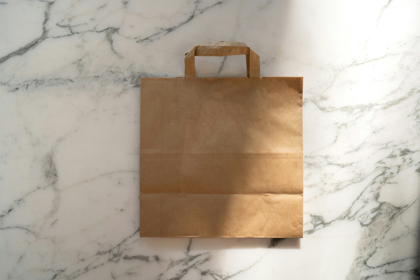 Plain paper takeaway bag on a marble counter, ready for a direct order