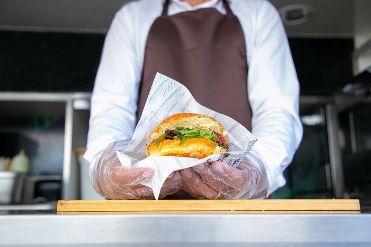 Cook handing over a freshly wrapped burger